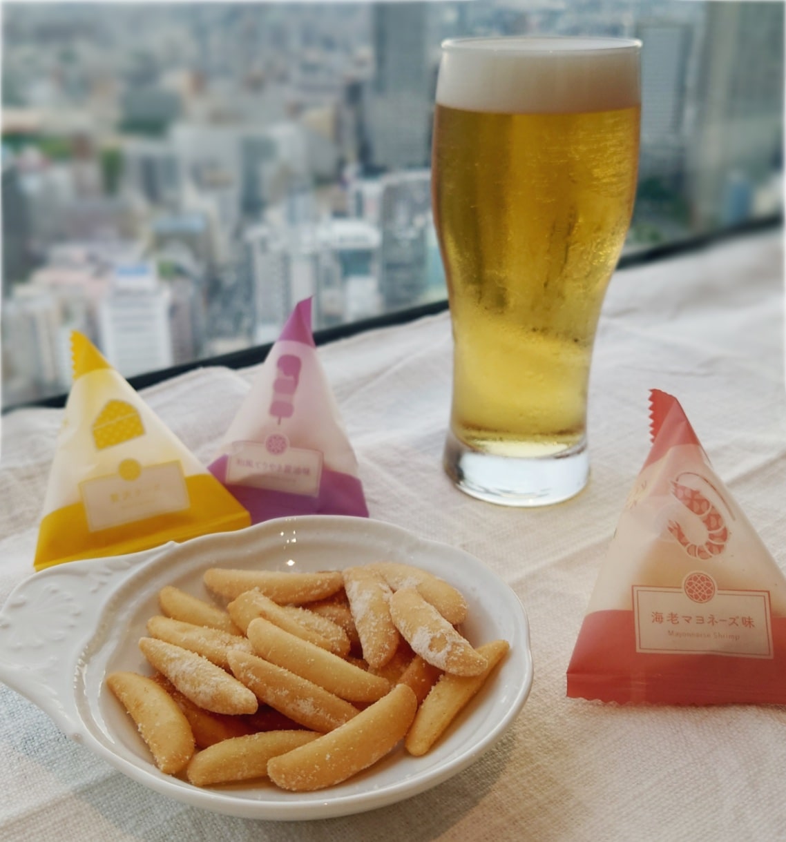 お皿に持ったかきたねと小袋とビール